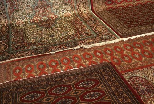 Close-up of intricately patterned traditional rugs laid on the floor.